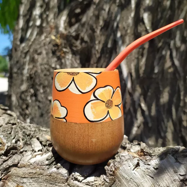 Mate pintado de naranja con diseño de flores y madera a la vista.