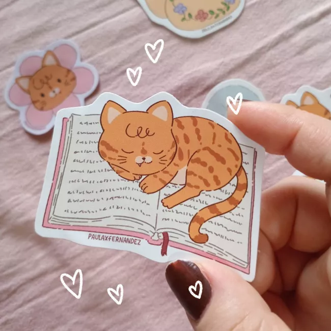 Sticker de gatito durmiendo en un libro